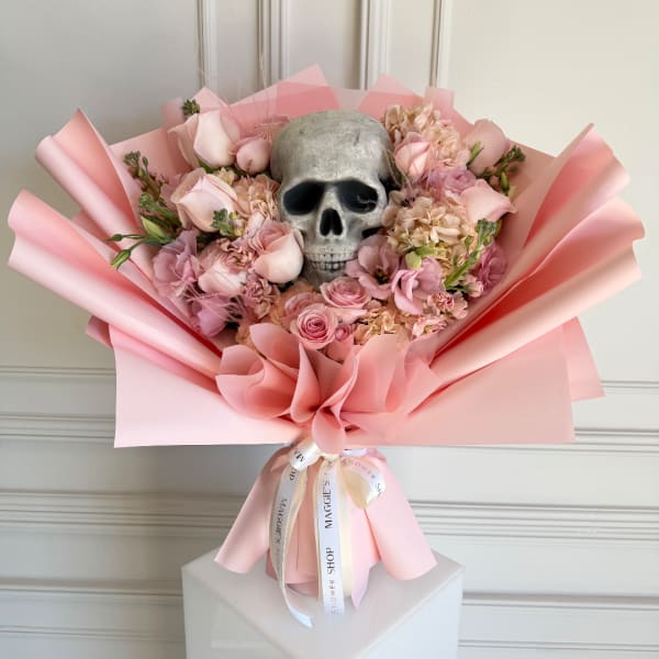 Pink bouquet with roses and a skull centerpiece wrapped in pink paper