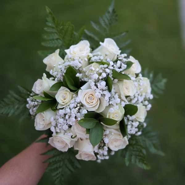 Handheld bouquet of white roses with baby's breath and greenery