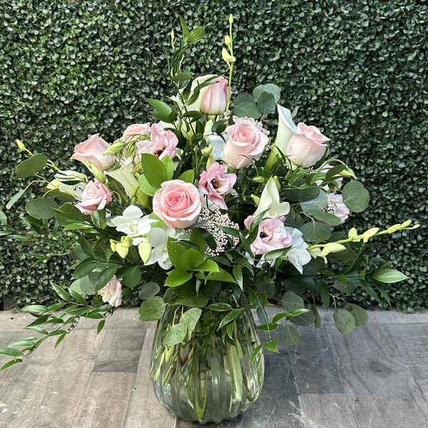 Pink roses and white calla lilies in a clear glass vase
