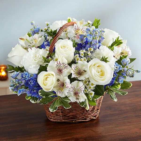 White roses and blue flowers arranged in a wicker basket