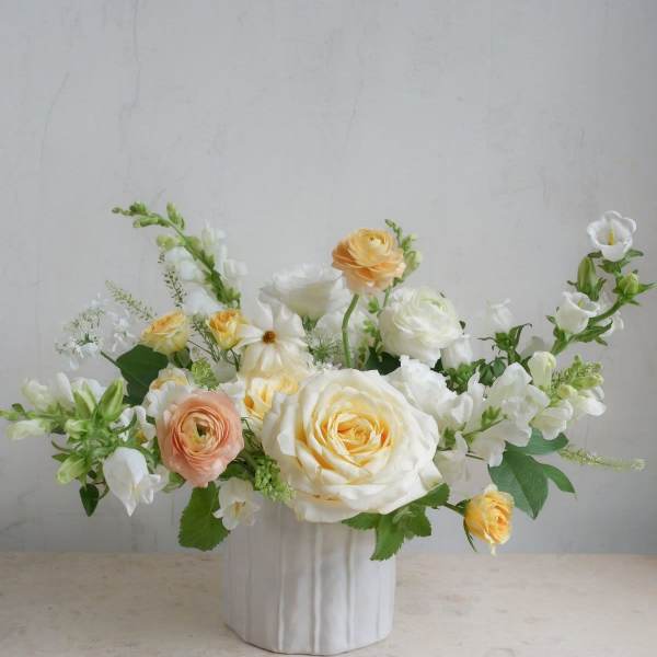 White and peach roses arranged in a white vase