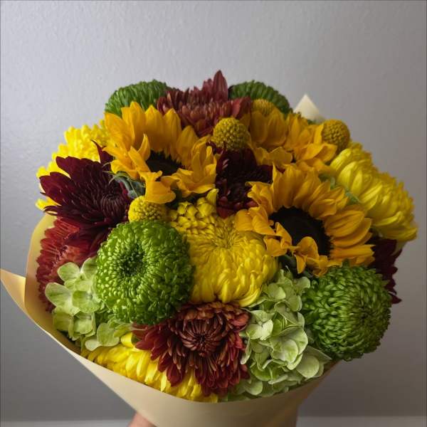 Bouquet of sunflowers and chrysanthemums wrapped in pale paper
