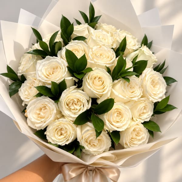 Bouquet of cream roses wrapped in white paper with a satin ribbon