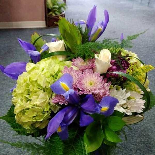 Bouquet of purple irises, hydrangeas, and mixed blooms in a basket