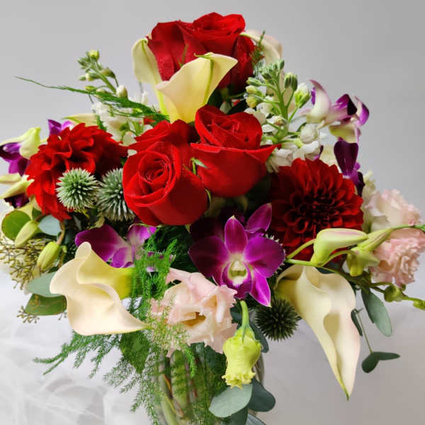 Bouquet of red roses, white calla lilies, and purple orchids in a vase