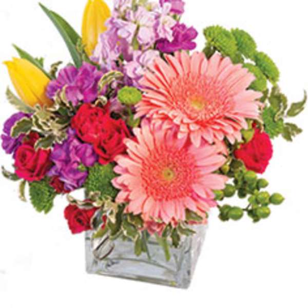 Mixed bouquet in a clear square vase with pink gerbera daisies and colorful blooms