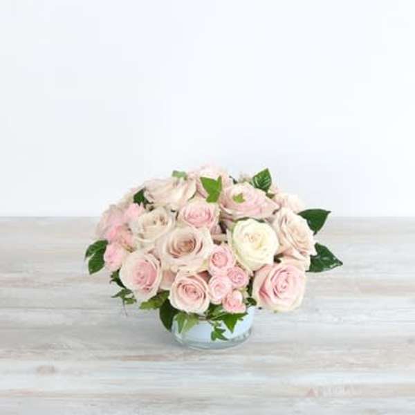 Low bouquet of pale pink and white roses in a clear glass bowl