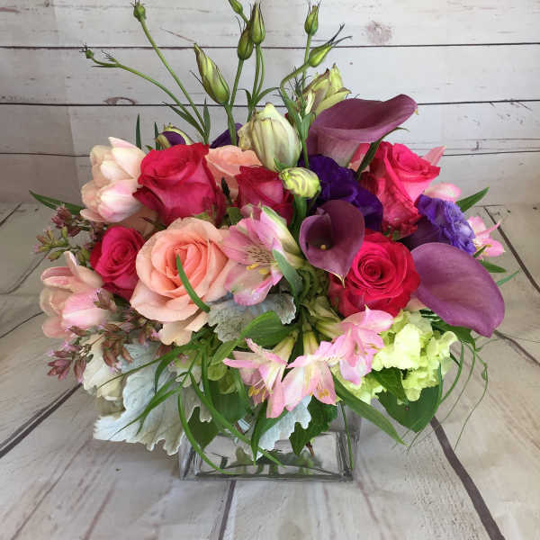 Mixed bouquet of roses, calla lilies, and lilies in a glass vase