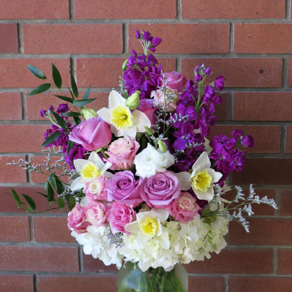 Mixed pink, white, and purple flowers in a glass vase