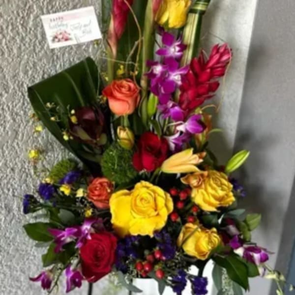 Tall mixed floral arrangement with red tropical blooms and roses