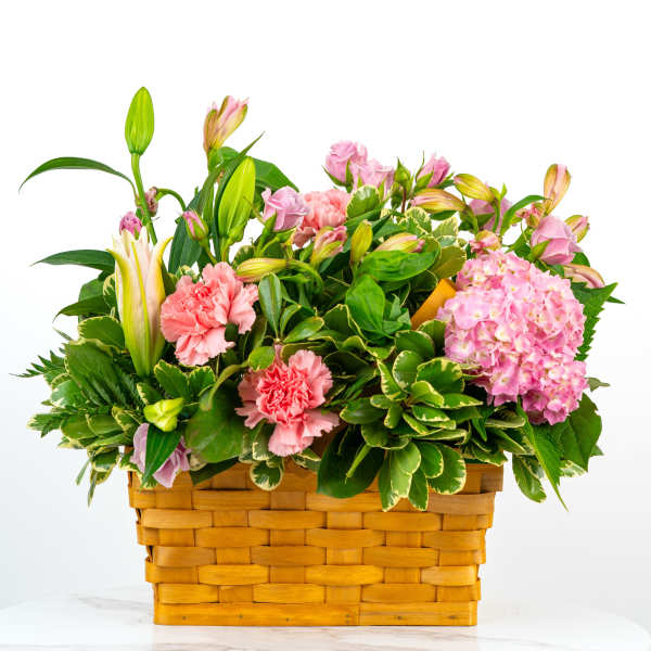 Pink flowers and lilies arranged in a woven basket