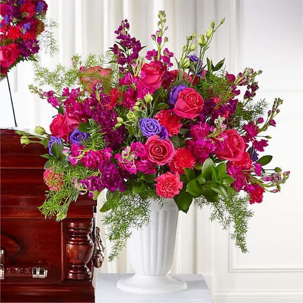 Bright pink and purple floral arrangement in a white vase