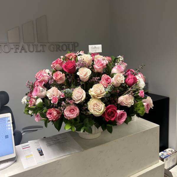Large pink and cream rose arrangement in a white vase