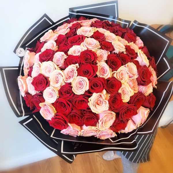 Large bouquet of red and blush pink roses wrapped in black paper