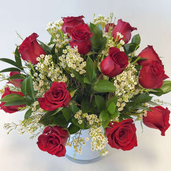 Red roses arranged in a clear glass vase with white filler flowers