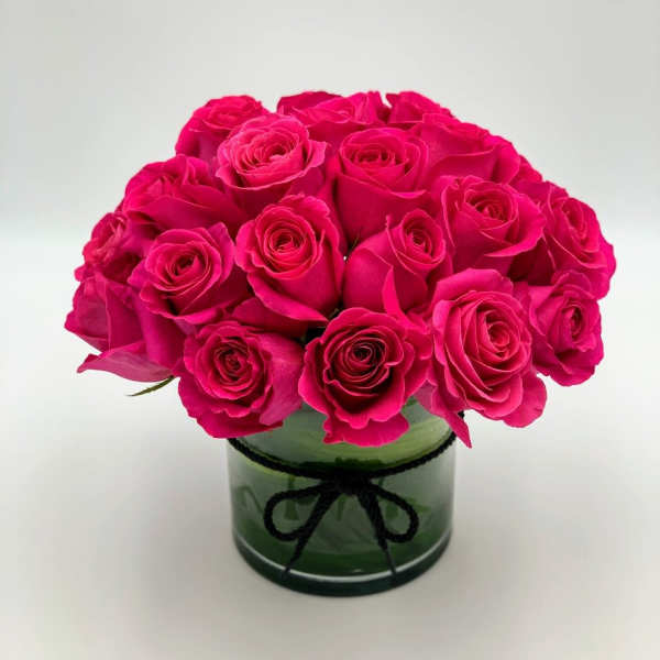 Bouquet of hot pink roses in a green glass vase with a black ribbon