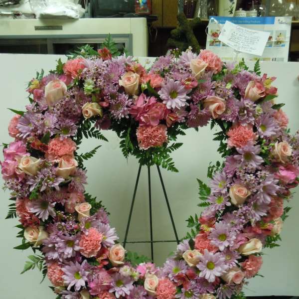 Heart-shaped floral wreath with pink and lavender blooms on an easel