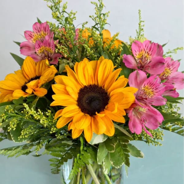 Bouquet of yellow sunflowers and pink alstroemeria in a glass vase