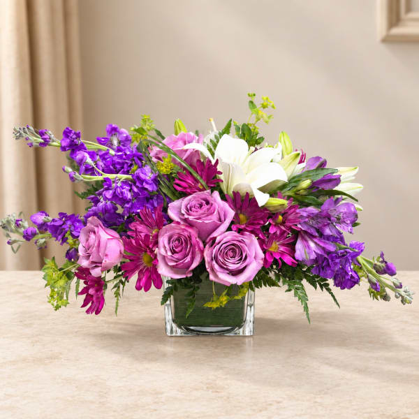 Purple and pink mixed bouquet in a square glass vase