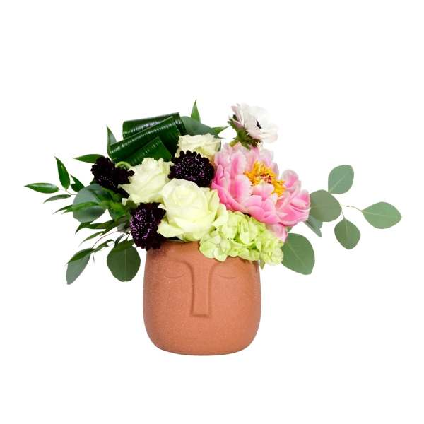 Pink and white flowers in a terracotta face vase
