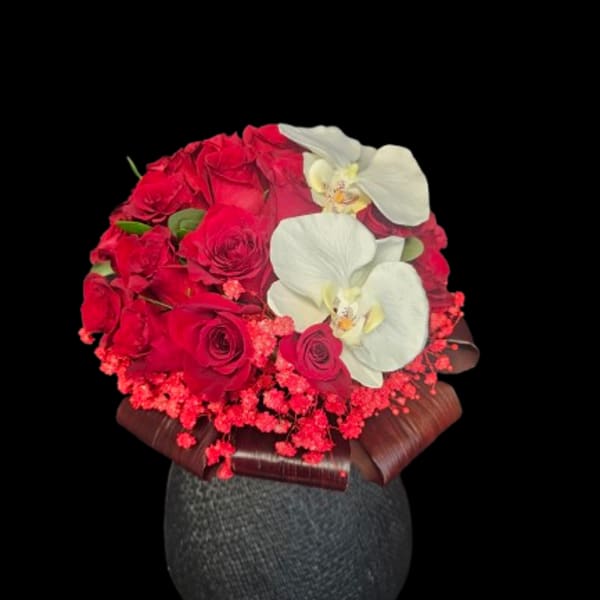 Red roses with white orchids in a dark vase