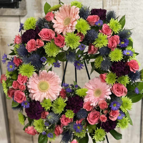 Heart-shaped floral wreath with pink roses and gerbera daisies on a stand