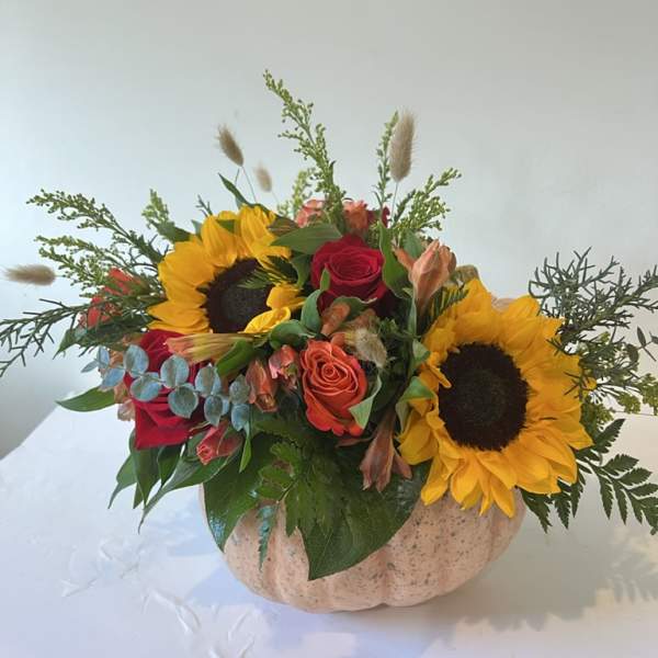 Sunflowers and roses arranged in a pumpkin-shaped container
