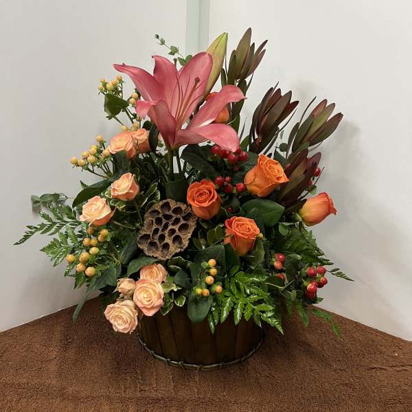 Pink lilies and orange roses arranged in a basket with berries
