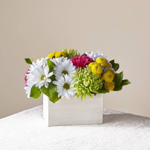 Mixed bouquet of white, yellow, and pink flowers in a white box