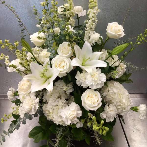 White roses and lilies arranged with tall white blooms in a vase