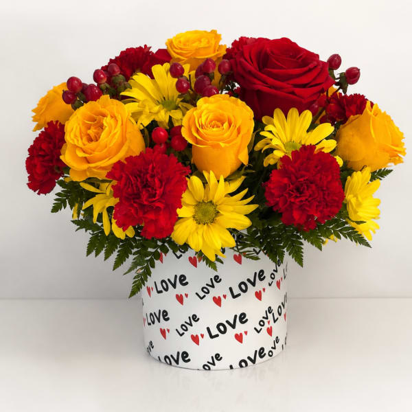 Red and yellow flowers arranged in a heart-themed box