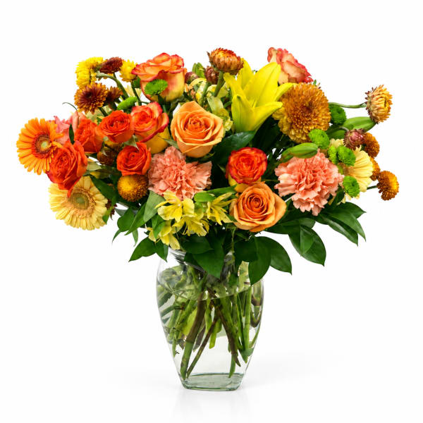 Colorful bouquet of roses, lilies, gerbera daisies, and carnations in a glass vase