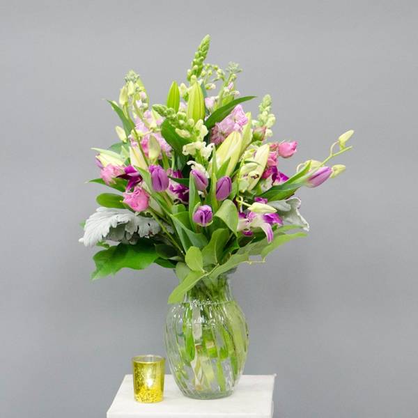 Mixed bouquet of lilies and pink-purple flowers in a glass vase
