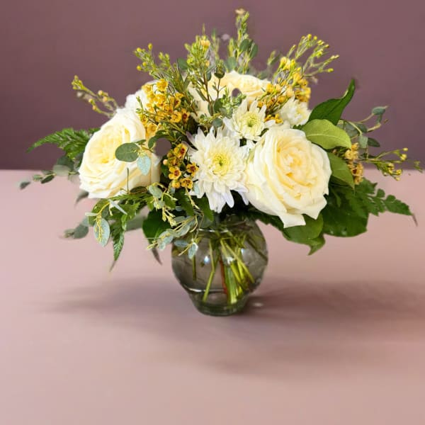 White roses and daisies arranged in a glass vase
