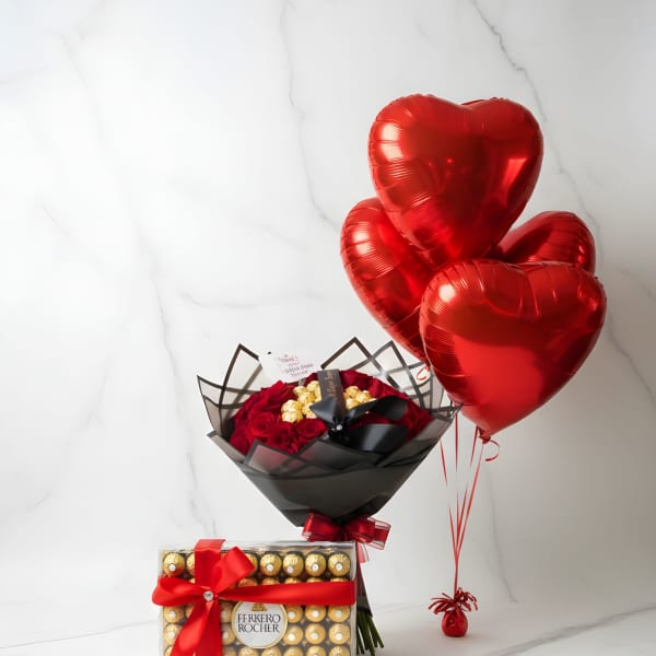 Red heart balloons beside a bouquet of red roses and a Ferrero Rocher gift box