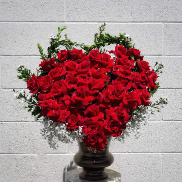 Heart-shaped arrangement of red roses in a dark vase