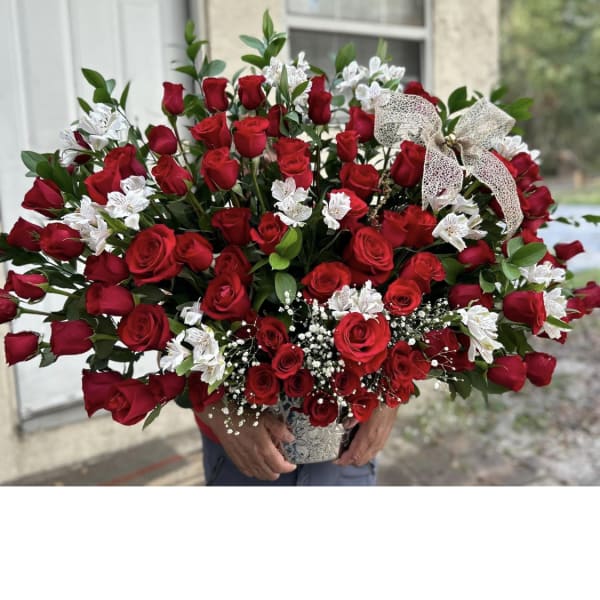 Large bouquet of red roses with white filler flowers in a decorative vase