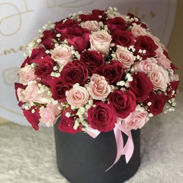 Round bouquet of red and blush roses in a black box with a pink ribbon