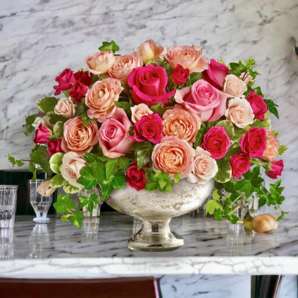 Pink and peach roses arranged in a silver pedestal bowl