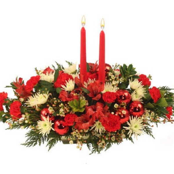 Red and white floral centerpiece with two red taper candles and shiny red ornaments.