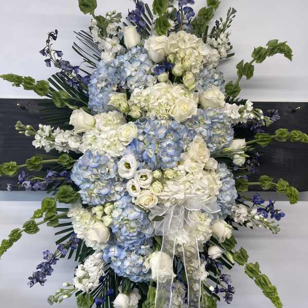 Large white and blue floral spray with ribbon on a black stand