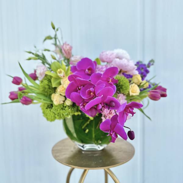 Purple orchids and mixed pastel flowers in a glass vase