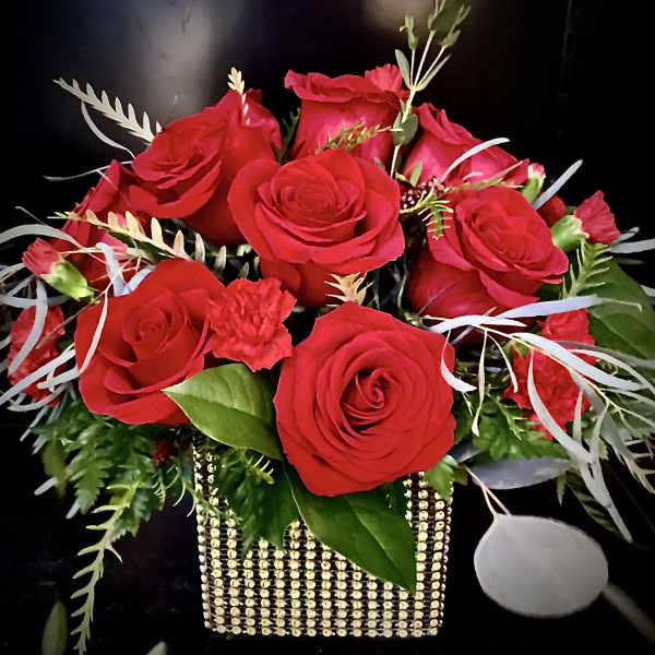 Arrangement of red roses and small red flowers in a gold beaded cube vase