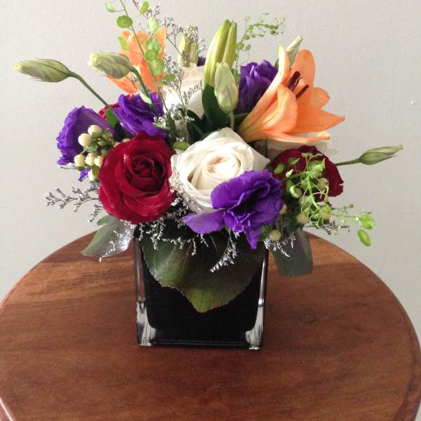 Mixed bouquet of roses and lilies in a black square vase