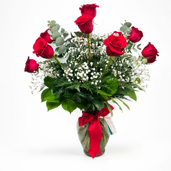 Red roses in a glass vase with baby's breath and greenery