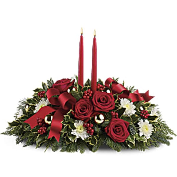 Red rose centerpiece with two red taper candles and holiday greenery