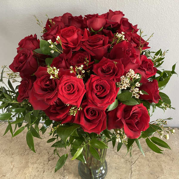 Bouquet of red roses in a glass vase with greenery