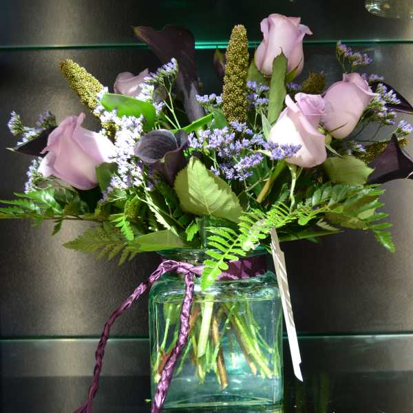 Lavender roses and purple filler flowers in a glass vase