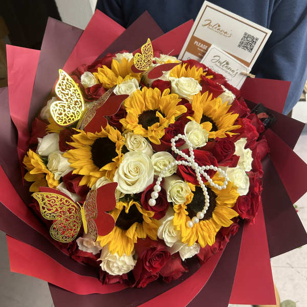 Bouquet of red and white roses with sunflowers in burgundy wrap