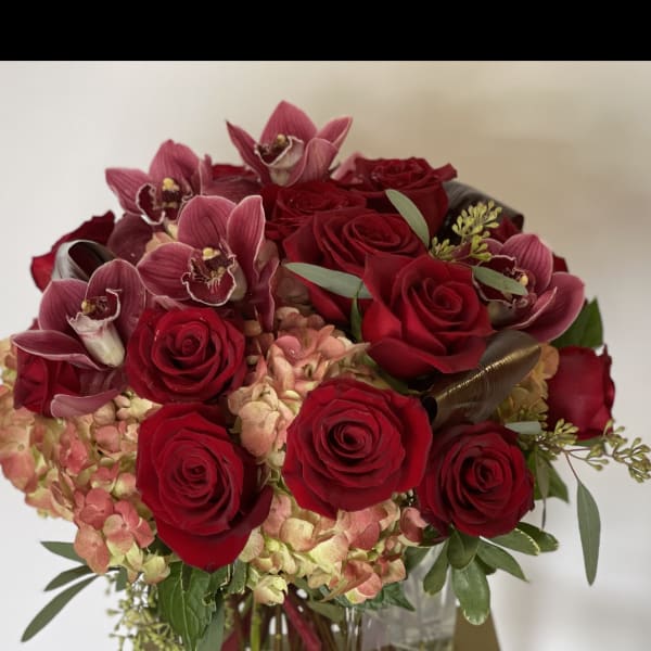 Red roses and pink orchids in a square glass vase